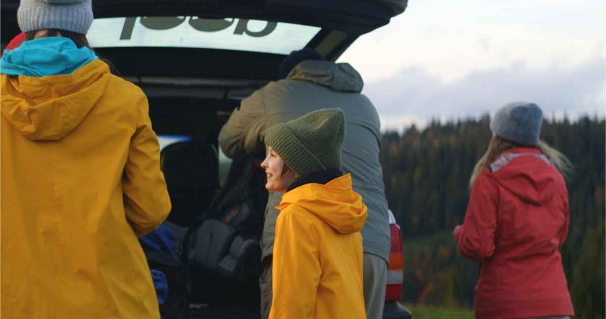 Family packing their suitcases in the trunk of a camper 