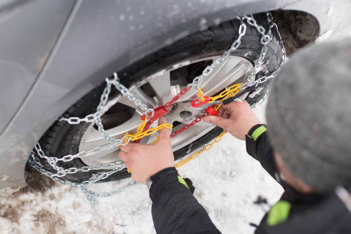 Driver putting on snow chains in his vehicle rear wheel