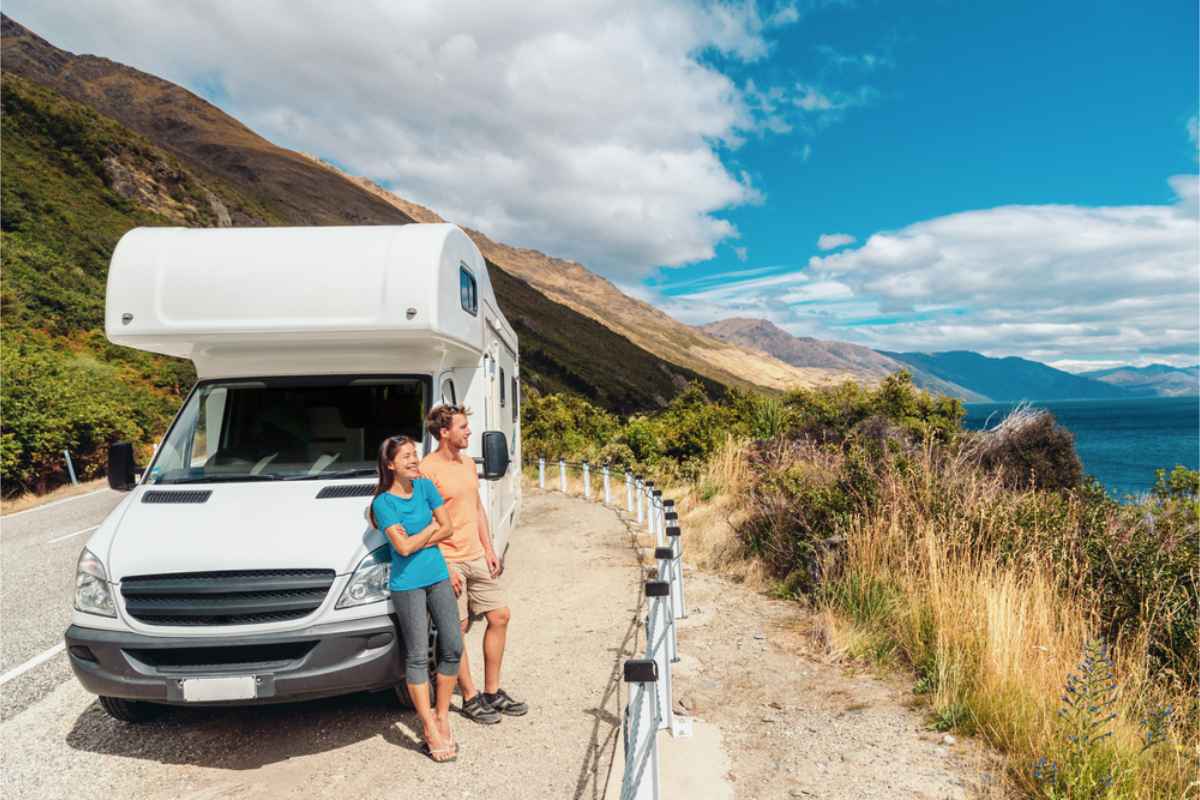 Tourists standing by their motorhome while in a road trip through NZ