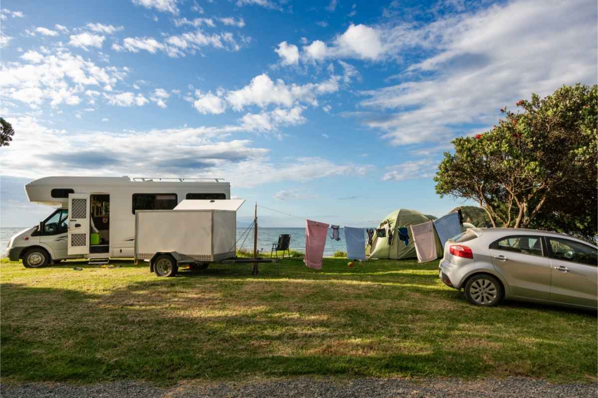 Motorhome and car parked by the beach with the whole camping set up