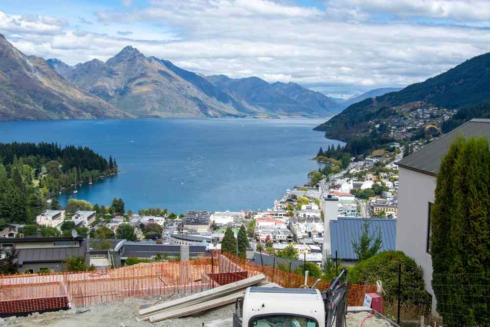 Panoramic view over Queenstown and Lake Wakatipu, with steep mountains framing the water and the town spread along the lakeshore.